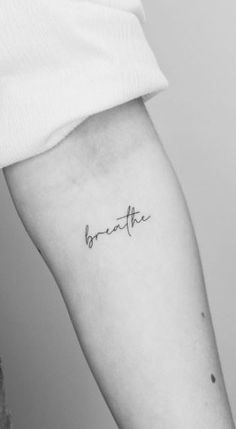 a woman's arm with the word breathe tattooed on it