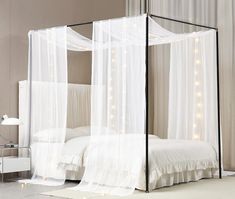 a canopy bed with white curtains and lights on the side wall in a modern bedroom