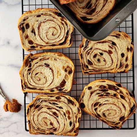 An overhead shot of 5 slices of cinnamon raisin swirl bread on a cooling rack with a teaspoon of cinnamon off to the left side. Overnight Raisin Bread, Sourdough Cinnamon Raisin Bread Clever Carrot, Quick Cinnamon Raisin Bread, Cinnamon Raisin Artisan Bread, Cinnamon Raisin Banana Bread, Easy Cinnamon Swirl Bread, Healthy Raisin Bread, Best Cinnamon Raisin Bread Recipe, Easy Cinnamon Raisin Bread