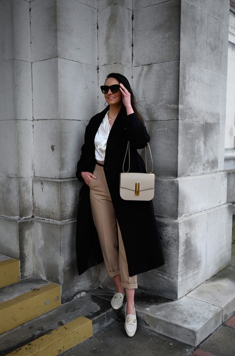 Wearing the Vancouver cross-body bag in a stunning taupe-coloured smooth leather from DeMellier London. Stone-coloured trousers complimented with a gold clasp black leather belt, on top a white silk bow tie blouse for added texture. Wrapped up in Other Stories belted wool coat in black. The look is completed with some neutral sophisticated leather loafers. #DeMellierLondon #DeMellierBag #Luxury #LuxuryHandbag #LuxuryCrossbodyBag #Taupe #TaupeBag #LuxuryStyling #ootd #designerbag White Bag Outfit Winter, Demellier Vancouver Bag, Taupe Purse Outfit, Demellier Vancouver Bag Outfit, Demellier Bags Outfit, Taupe Bag Outfit, Chloe Marcie Bag Outfit, Demellier Bags, Demellier London