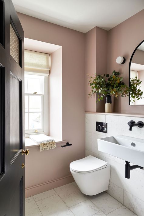 Dusty pink bathroom with contrasting black tapware. Marble tiles and a feature mirror and wall light. Pretty styling and greenery Blush Colored Bathroom, Pink Downstairs Toilet, Moody Pink Bathroom, Dusky Pink Bathroom, Rose Pink Bathroom, Mauve Bathroom Ideas, Dusty Rose Bathroom, Pale Pink Bathroom, Blush Pink Bathroom