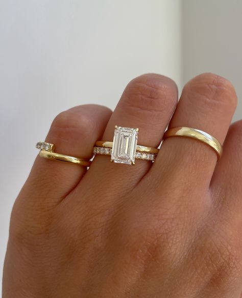 A stunning emerald cut solitaire engagement ring paired with a classic pave wedding ring.