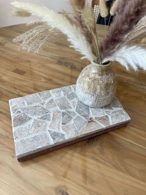 I had some leftover tile pieces and a piece of timber so decided to make a mosaic tiled table centrepiece! This would make a really good gift too. Firstly find a piece of timber for the base of the centrepiece. I had this travertine tile leftover from our pool landscaping. It’s a beautiful stone tile, I just needed to break it up into smaller pieces. To do this I dropped it onto the ground, then used a hammer to break it into smaller pieces. I then tested the design prior to g… Projects With Tiles Scraps, Craft Ideas For Leftover Tiles, Using Leftover Tiles Diy Projects, Coasters Out Of Tiles, Tile Diy Projects, Mosaic Gift Ideas, Diy Tile Trivet, Leftover Tile Projects, Diy Mosaic Tiles