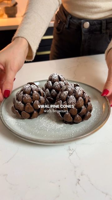 Georgina Thomas on Instagram: "Viral brownies pine cones! I had to jump on this trend and make the famous pine cones but with a gooey brownie centre using my brownies recipe. If you have any leftover brownies then this is such a cute idea for the holidays ✨🤎 Ingredients 9 brownies (see recipe on my page) Chocolate curl cereal 1-2 tbsp icing sugar Instructions 1. Make brownies (use my recipe on my profile- 2 posts down) or buy brownies! 2. Squeeze them together to form a pine cone shape. Around 9 brownies should make 6 cones. 3. Use as much cereal as you need to surround the brownie pine cones. This takes a while so be persistent! 4. Sieve with icing sugar and enjoy! #pinecones #pine #viral #chocolatebrownies #brownies #christmas #christmasdessert #holidays" Brownie Pinecone Recipe, Pine One Brownie, Brownie Pine Cones, Brownie Pinecones With Almonds, Chocolate Pinecones Recipes, Leftover Brownies Ideas, Pine Cone Brownies, Pinecone Dessert, Brownie Pinecones