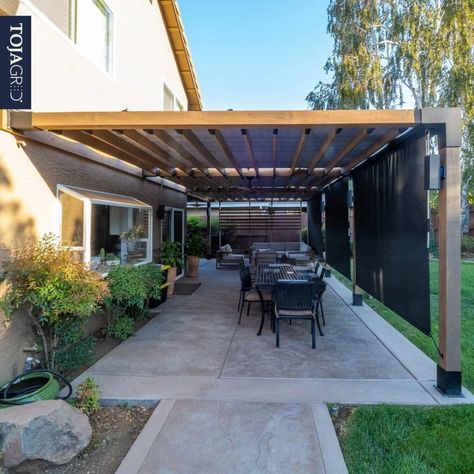 Modern Pergola Ideas To Spruce Up Your Yard – Forbes Home Pergola Connected To House, Slanted Pergola Attached To House, Pergola Against House, Metal Pergola Patio Ideas, Patio Awning Attached To House, Contemporary Pergola Designs, Modern Patio Cover, Attached Pergola Ideas, Backyard Shade Structure