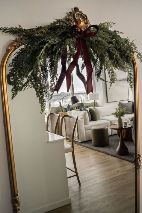 Anthropologie Mirror Christmas Decor, Mirror Swag Garlands, Christmas Mirror Decorations Diy, Gold Mirror Christmas Decor, Swag For Mirror, Christmas Decor Greenery, Mirror With Garland Christmas Decor, Pine Swags Christmas, Christmas Garland Mirror Decor