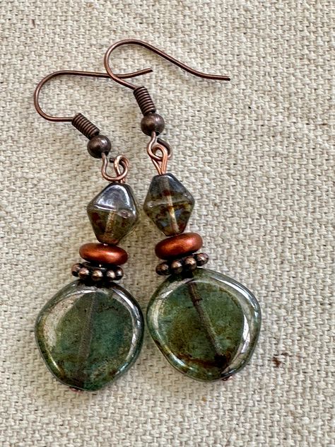 Beautiful  transparent Lumi green glass.  An earthy picasso coat is added giving earthy touches to the entire surface of the coin beads. They are beautiful coin beads. They have a matching 8mm beautiful and earthy pine green bicone glass bead.  They have a glossy fire polished lumi finish. The earrings dangle an inch on Copper Ear Wires.  The copper accents bring out the earthy feeling of these unique earrings. Perfect for work or casual anytime of year. UniquelybyRuth pays for your first class shipping when your order is $35 or more, so take a look around the shop and see if anything else calls to you! 🆓 Earth Tone Earrings, Chip Bead Earrings, Earth Decor, Diy Beaded Earrings, Earthy Jewelry, Belly Jewelry, Copper Accents, Green Jewelry, Funky Jewelry