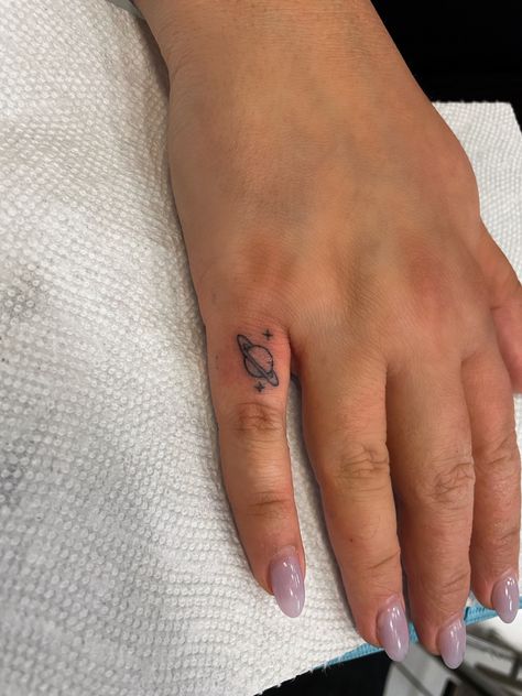 Tiny finger tat saturn tattoo space stars Universe Finger Tattoo, Star Finger Tat, Saturn Tiny Tattoo, Saturn Wrist Tattoo, Saturn Hand Tattoo, Mini Saturn Tattoo, Saturn Tattoo With Stars, Dainty Saturn Tattoo, Planet Hand Tattoo