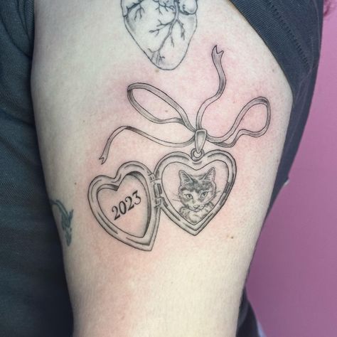 Heart locket ft. Bean 🥺 the cutest little cat 🐱💕 . . . . Tattooed @havenstudionyc. Currently booking June & July . . . . . . . . . #lockettattoo #cattattoo #catlovers #finelinetattoo #finelinetattooartist #nyctattooer #nyctattooartists #ladytattooers #cutetattoo #femaletattooartist #newyorkcity #femininetattoos #delicatetattoos #cutecat #petportraittattoo #catstagram #brooklyn #tattooartistbrooklyn Cat Heart Locket Tattoo, Pretty Cat Tattoos, Custom Cat Tattoo, Heart Shaped Locket Tattoo, Dog Locket Tattoo, Pet Locket Tattoo, Cat Pet Tattoo, Cat Locket Tattoo, Open Locket Tattoo