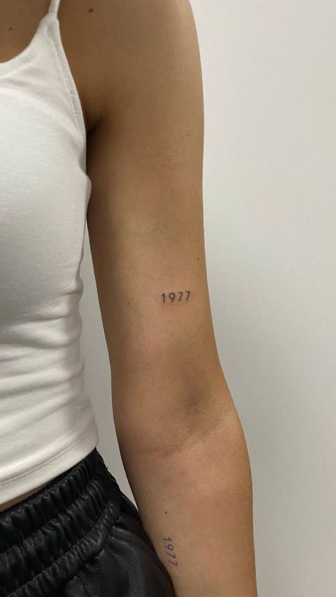 Date Placement Tattoos, Minimalist Tattoo On Arm For Women, Date On Back Of Arm Tattoo, Year Tattoos On Arm, Dainty Tattoos Year, Year Tattoo Number Dainty, Mini Date Tattoo, Above Arm Tattoo, Medium Tattoo Ideas Men