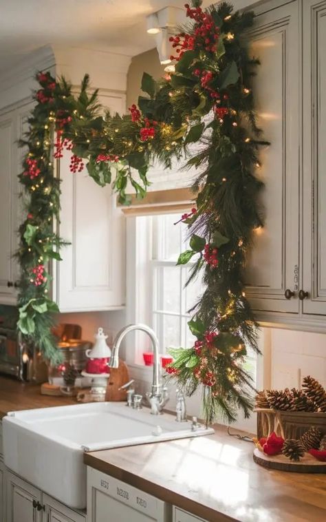 25 Stunning Christmas Kitchen Decor Ideas to Try This Season Christmas Garland On Kitchen Cabinets, Holiday Kitchen Window Decor, Garland Over Kitchen Cabinets, Christmas Home Decor Kitchen, Red Christmas Kitchen Decor, Christmas Kitchen Garland, Traditional Christmas Kitchen Decor, Christmas Decor Kitchen Window, Vintage Christmas Decor Ideas Kitchen