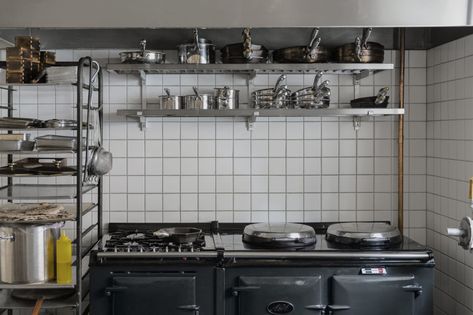 The small kitchen behind the bar (shown here when service is not in session) has simple components: floor-to-ceiling square tile, a charcoal-colored Aga range, and stacks of pots and pans. Small Kitchen Restaurant Design, Small Kitchen Restaurant, Small Restaurant Kitchen Design, Small Restaurant Kitchen, Kitchen Restaurant Design, Small Restaurant Interior, Restaurant Kitchen Design, Kitchen Workshop, Small Restaurants