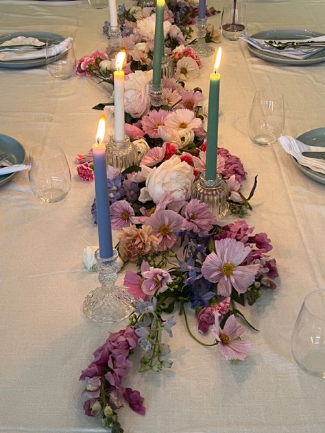 Pink purple blue pastel flower arrangement on dining table with candle sticks and blue ceramic dinner set for birthday dinner party Flower Aesthetic Birthday Party, Maximalist Table Decor, Floral Party Table Decor, Flower Themed Party Aesthetic, Circle Table Set Up, Flowers Laying On Table, Floral Dinner Table Setting, Flower Dinner Party Aesthetic, Wildflower Dinner Party