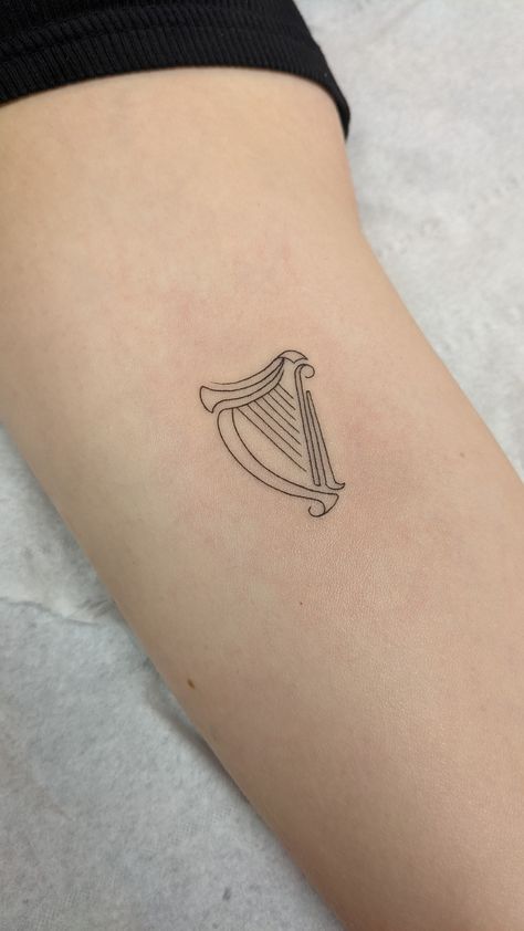 Fineline delicate Irish harp tattoo Simple Harp Tattoo, Ireland Harp Tattoo, Harp Tattoo Minimalist, Unique Irish Tattoos, Irish Dance Tattoo, Irish Symbols Tattoos, Small Ireland Tattoo, Irish Harp Tattoos For Women, Guinness Harp Tattoo