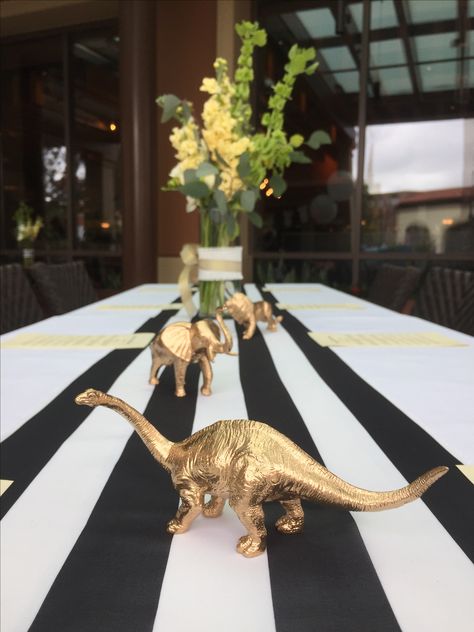 Gold dinosaurs, black and white for the momma to be Black And White Dinosaur Party, Black And Gold Baby Shower Ideas, Gold Dinosaur Party, Simple Dinosaur Centerpieces, Black And White Baby Shower Ideas, Dinosaur Golden Birthday, Tree Centerpieces For Dinosaur Party, Dinosaur Flower Centerpiece, Gold Dinosaur Decor