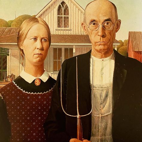 Grant Wood painted this portrait the way a theater director puts on a show. First he discovered the setting. Wood saw the house, now famous for inspiring American Gothic, in a small Iowa town and knew it had to be in a painting. Then he cast his sister and dentist to play the two roles. Many presume them farmer and daughter. But that’s never been nailed down. In fact, the painter left it ambiguous on purpose. Learn more with a click to LadyKflo’s Art Blog. #americangothic #grantwood #region American Gothic House, American Gothic Painting, American Gothic Parody, Grant Wood American Gothic, Front Of A House, David Choe, Istoria Artei, Grant Wood, Jan Van Eyck