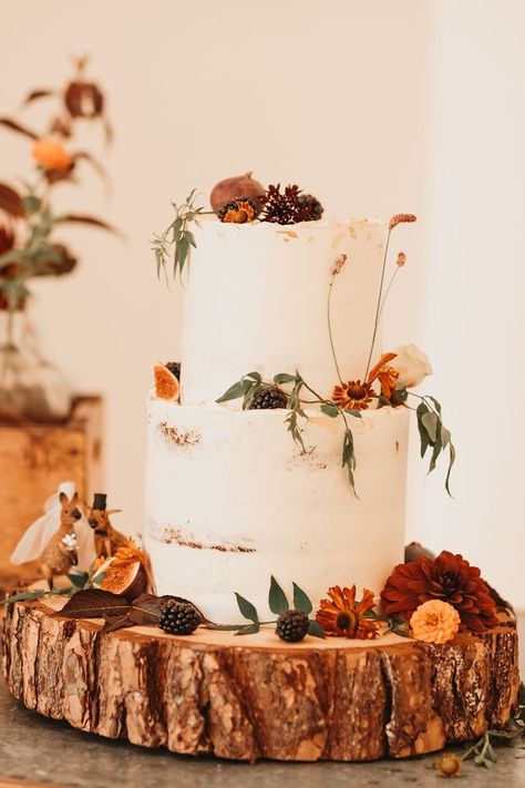 Set a serene fall day vibe with this simple two-tier wedding cake decored with figs, pine cones and wildflowers, click to learn more rustic wedding cake ideas. Fall Wedding Cakes Two Tier, Autumnal Wedding Ideas, Cake Table Wedding Rustic, White Autumn Wedding, Autumnal Flowers Wedding, Autumn Cake Wedding, Rustic Autumn Wedding Cake, Orange Cake Wedding, Two Tier Wedding Cake Rustic