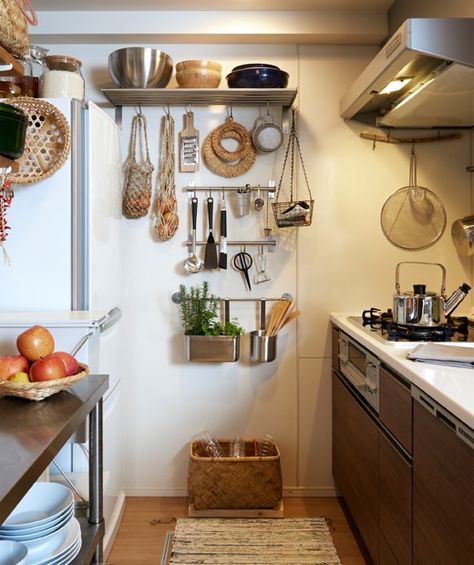 A narrow kitchen with dark cabinets and utensils hanging on metal rails and shelves on the end wall. Organiser Cucina, Kitchen Wall Storage, Narrow Kitchen, Small Kitchen Storage, Tiny Space, Dark Cabinets, Apartment Kitchen, Tiny Kitchen, Decoration Inspiration