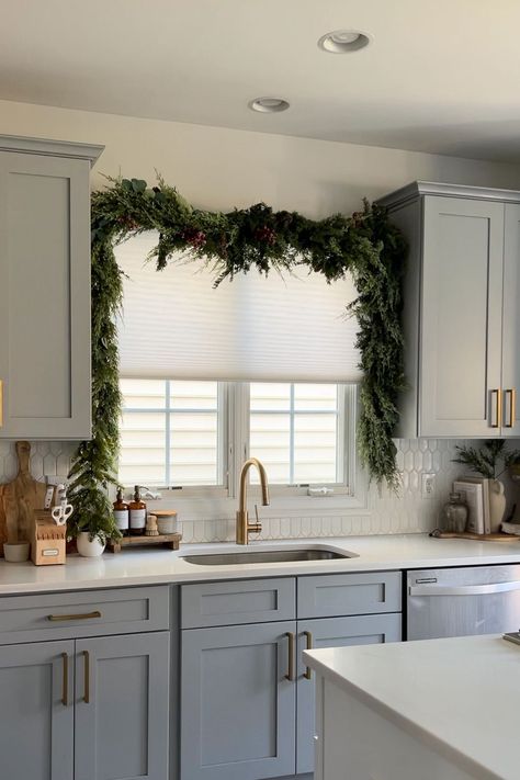 Here's Proof the Viral Christmas Garland Hack Taking Over TikTok Actually Works Garland Over Window Kitchen, Kitchen Island Garland, Christmas Garland Above Kitchen Sink, Garland Over Kitchen Sink Window, Christmas Garland Around Kitchen Window, How To Hang Garland Over Window, Above Sink Christmas Decor, Above Cabinet Garland, Christmas Wreath For Kitchen Cabinets