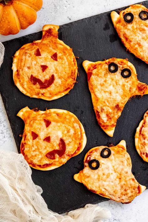 Kids will love these mini Halloween pizzas—especially if they get to put on the toppings themselves! These pizzas are perfect for a Halloween party or pre-trick or treat dinner. Halloween Pizza Recipes, Halloween Sleepover, Halloween Pizza, Recetas Halloween, Spooky Snacks, Halloween Fest, Halloween Movie Night, Halloween Food Treats, Easy Halloween Food