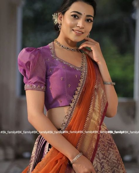 Do you need a beautiful and unique half saree for your next special occasion? Look no further than this lavender and orange Banarasi Silk lehenga! This gorgeous blouse features a collared V-neckline and puff sleeves with lace detailing on the yoke and sleeves, and the fabric used for it is golden tissue silk. The back of this dress is surely a head-to-turn pattern. It is paired with an organza silk-bordered dupatta. Whether you’re attending a wedding, a party, or a family occasion, this Banar... Half Sleeve Blouse Designs, Front Blouse Designs, Lavender And Orange, Blue Blouse Designs, Netted Blouse Designs, Long Blouse Designs, New Saree Blouse Designs, Latest Model Blouse Designs, Lehenga Blouse Designs