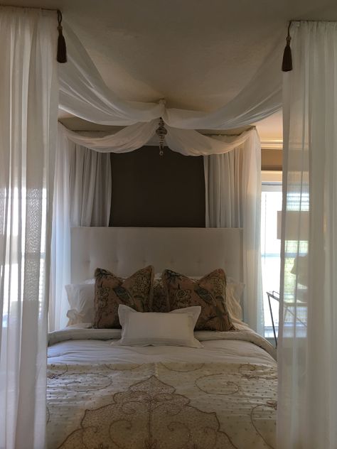 Create a romantic canopy retreat for your Bedroom.  Draping a sheer fabric to mimic a canopy from the ceiling adds a soft elegant touch to an ordinary space.  This can be a very simply and inexpensive thing to do while adding a lot of look. Bed With Sheer Curtains, Drapes From Ceiling Bedroom, Beds With Curtains Canopy, Drapes Over Bed Boho, Elegant Bed Canopy, Bedroom Draping Ceiling, Bedroom Ceiling Canopy, Black Mesh Bed Canopy, How To Create A Canopy Ceiling