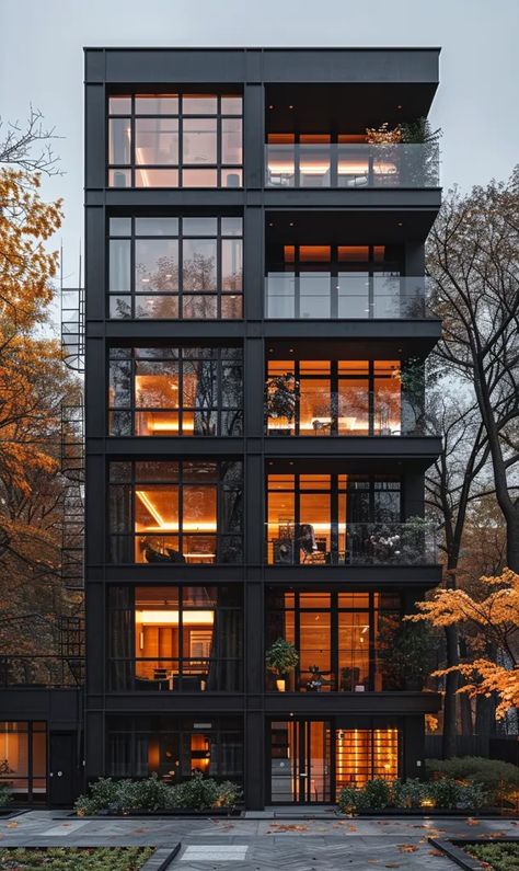 The image is of a modern apartment building with a black exterior and large windows. The building is surrounded by trees with orange autumn leaves ->> more details in ai-img-gen.com Apartment Modern Exterior, Apartments Design Exterior, Loft Apartment Building Exterior, Outside Apartment Building, Two Story Apartment Building, Fancy Apartment Building Exterior, City Apartments Exterior, High Rise Apartment Building, New York Apartment Exterior Building