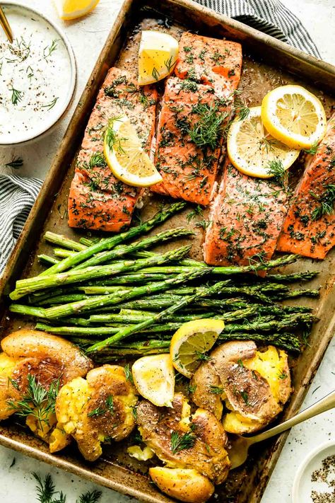 This Sheet Pan Salmon and Asparagus with Crispy Smashed Potatoes is an easy all-in-one dinner, perfect for springtime! Salmon fillets, seasoned with lemon & dill, bake on a sheet pan with asparagus spears until perfectly tender & flaky. Serve with crispy smashed potatoes (oven-roasted alongside the salmon!) & dill yogurt sauce to bring all the flavors together. A fresh & healthy weeknight dinner! #salmonandasparagus #salmonandpotatoes #sheetpansalmon #bakedsalmon #salmonrecipes #easydinnerideas Salmon Sheet Pan Dinner, Clean Eating Salmon, Dill Yogurt Sauce, Potatoes Oven, Salmon Dill, Baked Salmon And Asparagus, Rosemary Salmon, Sheet Pan Salmon, Salmon Asparagus