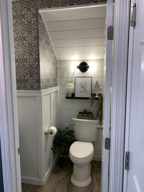 a modern farmhouse powder room under the stairs, with a shiplap wall, printed wallpaper, an open shelf and some decor and greenery Tiny Toilet Room Ideas Farmhouse, Under Stairs Bathroom Full, Under The Stair Bathroom, Powder Bathroom Under Stairs, Small Bathroom Under Stairs Ideas, Under The Eaves Bathroom, Half Bathroom Under Stairs Decor, Guest Bathroom Under Stairs, Bath Under Stairs Ideas