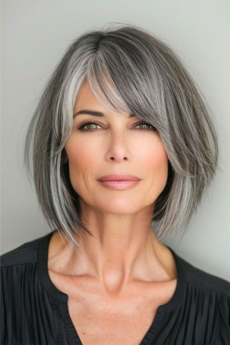 A smoky salt and pepper bob combines the edge of sharp angles with the softness of feathered layers. The color seamlessly transitions back and forth from black to gray, offering a modern twist on the classic bob. Click here to see more stunning bob hairstyles for women over 60. Medium Salt And Pepper Hairstyles, Shoulder Length Salt And Pepper Hair Over 50, Narrow Face Haircuts, Bobs For Grey Hair Over 50, Grey Layered Bob Hairstyles, Hair Color Ideas For Women 60, Trendy Gray Hairstyles, Short To Medium Bob Hairstyles, Styles For Thick Straight Hair