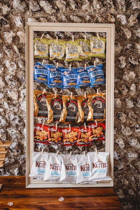 crisp wall at Cissbury Barns wedding in sussex Crisp Wedding Wall, Crisp Board Wedding, Wedding Snack Station Ideas, Wedding Crisps Wall, Wedding Crisp Wall Ideas, Crisps At Wedding, Food Walls Wedding, Crisp Table Wedding, Pallet Crisp Wall Wedding