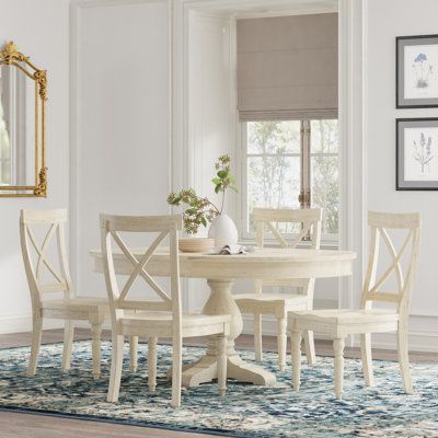 This 5-piece dining set completes the look of your eat-in kitchen or dining room. It includes a round table, an 18” leaf, and four X-back chairs - all in a purposefully distressed, whitewashed finish that lends French country appeal. The pedestal table has a solid wood base and a top made from solid and engineered wood. The chairs boast square seats, high backs, and turned legs that suggest a hand carved look. When you have guests, simply add the leaf to expand the table for a seated meal, or us White Wood Round Dining Table, White Top Kitchen Table, Beachy Kitchen Table And Chairs, White Round Kitchen Table Wood Chairs, Small Round Dining Table Coastal, Kelly Clarkson Dining Table, White Wash Round Kitchen Table, Farmhouse Pedestal Table, Round Kitchen Table And Chairs