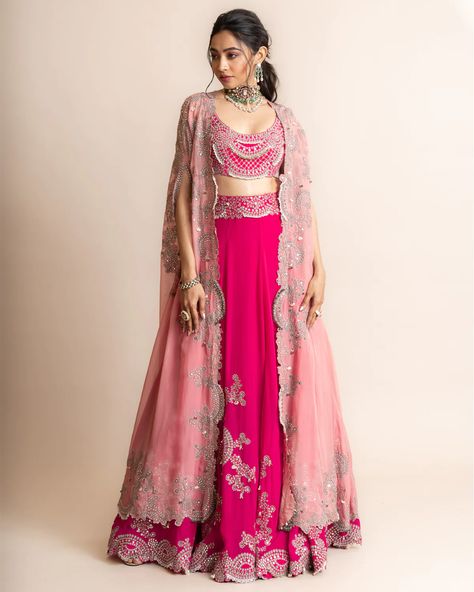 Old rose long shoulder gathered cape with mirror work, Swarovski, metallic sequins, studs and pearls embroidered on the border. Comes with fuchsia hand embroidered bias lehenga with attached can-can and a matching blouse. Unique Indian Outfits, U Neck Blouse, Nupur Kanoi, Modern Lehenga, Cape Lehenga, Baju Kahwin, Cape For Women, Mirror Work Lehenga, Dupatta Style