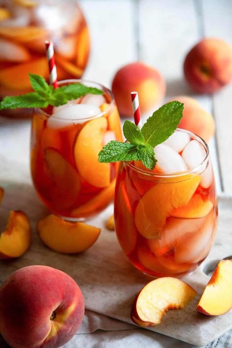 This simple, homemade Peach Tea starts off with a beautiful, pink-hued Peach Syrup that’s bursting with the flavor of fresh, sweet peaches. The peach simple syrup is then combined with perfectly brewed tea for the perfect summer beverage! Mango Sangria, Fuze Tea, Fourth Of July Drinks, Fruit Sangria, White Wine Sangria, Peach Syrup, Peach Sangria, Peach Ice Tea, Peach Tea