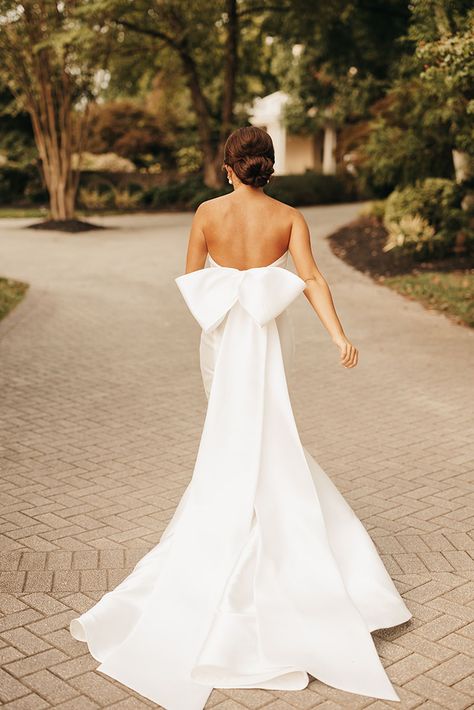 Classic and Elegant Summer Bride Style with a Full Neat Bridal Updo and Low Back Mermaid Fit Gown with Large Pressed Bow Wedding Dress With Back Out, Statement Bow Wedding Dress, Strapless Timeless Wedding Dress, White Wedding Dress With Bow, Vintage Chic Wedding Dress, Bow Wedding Dress Low Back, White Bow Wedding Dress, Wedding Dresses Romantic Elegant, Strapless Classic Wedding Dress