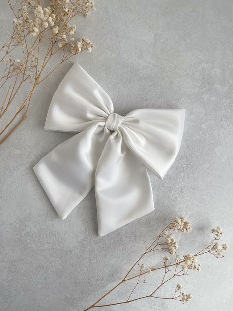 Large and Luxurious White Duchess Satin with tails hair bow.  This oversized hair bow is an ideal hair accessory for wearing to a special occasion, absolutely perfect as bridal hair bow for a wedding, hen party or evening reception!  It will also make a great "gift for girl." They are handmade with love and care from  high quality fabric in our studio in England. The bow measures  8" in width appx  12 cm or 4 3/4" in height  Tail is 18 cm or 7" long approximately  📍Attachments :  ✅Barrette  ✅Co Black Zip Up Hoodies, Bridal Bow, White Hair Bow, Large Hair Bow, Evening Reception, Giant Bow, White Hair Bows, Large Hair Bows, Duchess Satin