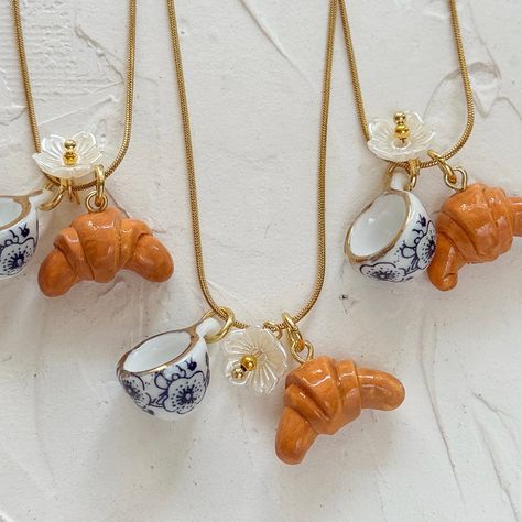 20 inch snake chain Featuring a hand sculpted and painted croissant charm, delightful bloom and blue chinoiserie teacup Diy Clay Necklace Charms, Ceramic Charms Diy, Diy Charms Jewelry, Aesthetic Clay Charms, Croissant Jewelry, Ua Aesthetic, Clay Charm Ideas, Ceramic Aesthetic, Polymer Charms