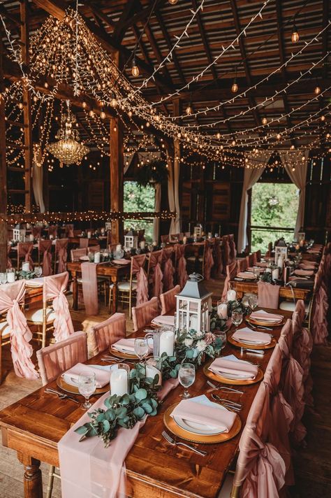 There is something magical about the look and feel of a barn wedding. It is a way to make a formal gathering to also be informal, relaxed, like a family get together. It also seems to make things stand out more, like the chandelier in this photo. Add in the beautiful farmhouse style tables and listen to the compliments. Wedding In Farmhouse, Farmhouse Theme Wedding, Wedding Venue Farmhouse, Farmhouse Decor Wedding, Rustic Princess Wedding, Country House Wedding Decor, Wedding Barn Lights, Rustic Wedding Set Up, Barnhouse Wedding Rustic