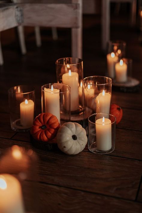 Boho wedding with autumnal wedding decor including pilar candles in hurricane vases and mini orange and white pumpkin decorations for the aisle Fall Centerpieces Wedding Pumpkin, Autumn Pumpkin Wedding Decor, Candle And Pumpkin Wedding Centerpieces, Candles And Pumpkins Centerpieces, Mini Pumpkin Centerpieces Wedding, Wedding Centerpieces Pumpkins, Autumn Wedding With Pumpkins, Gourds Wedding Decor, Fall Beach Wedding Table Decor