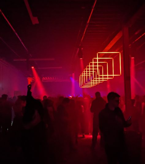 Photo of a darkened crowd in a warehouse made into an event venue lit by a line of square red lights Cyberpunk Bar, Warehouse Rave, Madison + Core + Aesthetic, Environment References, Peggy Guggenheim, Nightclub Design, Red Light District, Event Lighting, Event Inspiration