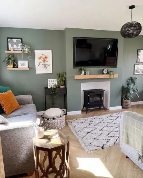 Picture of a cool green living room with a hearth, some shelves, a TV, a grey sofa with pillows, a a rug and some lovely and cool decor Grey Sofa With Pillows, Green Living Room Color Scheme, Living Room Design Green, Sage Living Room, Gray Sofa Living, Green Walls Living Room, Sofa With Pillows, Sage Green Living Room, Front Room Decor