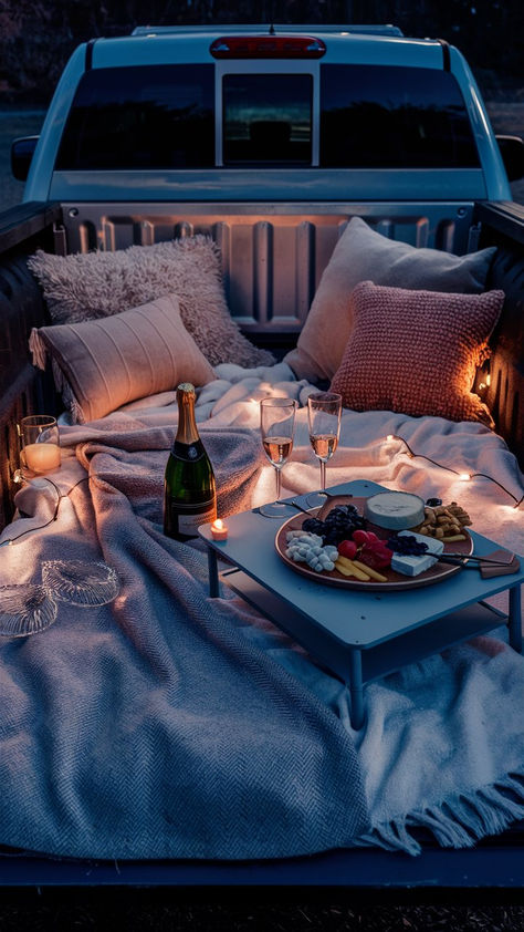 A cozy and romantic truck bed setup with pillows, blankets, candles, fairy lights, champagne, and a charcuterie board. Date Night Truck Bed, Date Night In The Back Of A Truck, Camping Love Romantic, Bed In Back Of Truck, Truck Bed Movie Night, Blanket Fort Date Night Romantic, Truck Movie Night, Tailgate Date Night Trucks Romantic, Pickup Truck Bed Date Night