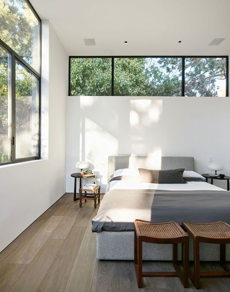 This modern master bedroom has a row of windows above the bed, with a second set of windows adding to the amount of the natural light the room receives. #ModernBedroom #BedroomDesign High Window Above Bed, High Windows In Bedroom, Bedroom High Windows, Bedrooms With Natural Light, Bedrooms With Two Windows, Natural Lighting Bedroom, Windows In Bedroom Ideas, Ceiling Window Bedroom, Window Bed Design