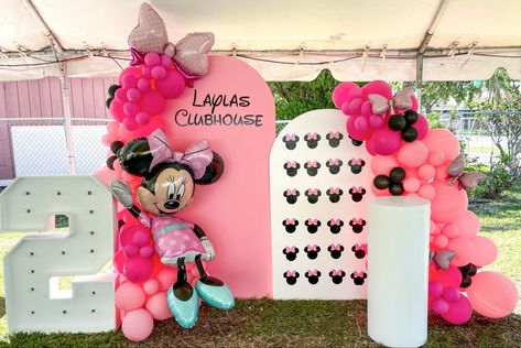 A birthday party featuring Minnie Mouse as the theme. Shades of pink and black balloons tied together and draped around a pink arched wall with the name Layla’s Clubhouse. Next to it, is a smaller white arch with patterned mickey ears. A marquee number 2 and white cake pedestal are placed on the sides of each backdrop. Minnie Mouse Balloon Garland, Minnie Mouse Backdrop, Mini Mousse, Minnie Mouse Balloons, Twodles Birthday, Minnie Mouse First Birthday, Birthday Minnie Mouse, Minnie Mouse Theme, Balloon Backdrop