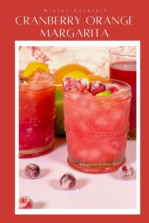 Glass filled with a cranberry orange margarita with sugared cranberries and lime slices as the garnish. Cranberry Orange Margarita Sangria, Frozen Cranberry Margarita Recipe, Pitcher Cranberry Margaritas, Cranberry Margaritas For A Crowd, Orange Cranberry Drink, Cranberry Orange Alcoholic Drinks, Cranberry Orange Drinks Alcohol, Cranberry Orange Cocktail Drink Recipes, Cranberry Pomegranate Margarita