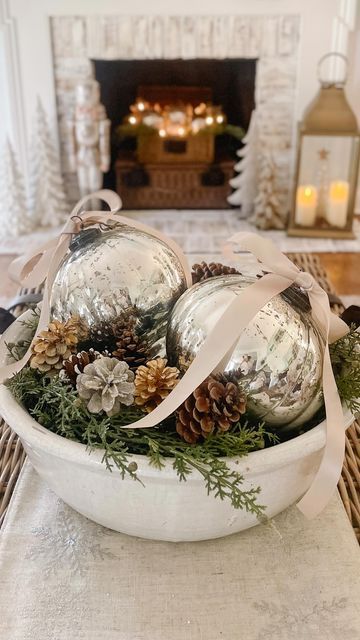 Jenny Brooks • Bloom Interior Designs on Instagram: "Easy centerpiece idea! ✨ And the best part is these fabulous oversized mercury ornaments are on sale for $15! Grab a large bowl, some greenery, 2 ornaments, pinecone filler, and ribbon…because bows make everything better! 🤍 I linked the ornaments and several bowl options for you. Just tap the link in my bio for details… #holidaycenterpiece #christmastabledecor #centerpiecesideas #christmasdecor #holidayhomedecor #christmascenterpiece #coffeetablestyling" Bread Bowl Decor Centerpieces Winter, Decorating With Large Ornaments, Christmas Bowl Centerpiece Ideas, Ornament Arrangement Ideas, Ornaments In Bowl Decor, Christmas Bowl Fillers Ideas Centerpieces, Coastal Christmas Centerpiece Ideas, Christmas Dough Bowl Table Centerpieces, Large Decorative Bowl Filler Ideas