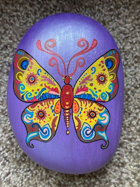 Hand painted on a large heavy rock is a folklore butterfly done in yellows, reds, oranges, and blues on a purple pearl background.  Topped with dragonfly glaze.  I used some metallics also.   Measures 5 1/2" x 4 1/2" x 2 1/2".   Sealed with varnish to help preserve the art. THE BACK IS NOT PAINTED so you may see the raw rock.  Thank you! Pearl Background, Heavy Rock, Painting Rocks, Purple Pearl, Butterfly Painting, Painted Rock, Dot Painting, Beautiful Butterflies, Rock Art