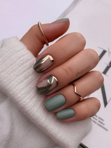 Combining matte sage green with shiny gold geometric lines, this nail design exudes modern sophistication. The minimalistic yet bold design on the accent nails adds a touch of luxury, while the muted green base keeps the look fresh and contemporary. Ideal for those who appreciate a blend of simplicity and elegance in their manicure. Shiny And Matte Nails, French Tips Light Blue, Gold Geometric Nails, Sage Green And Gold, Geometric Nails, Winter Nail Ideas, Modern Nails, Muted Green, Geometric Nail