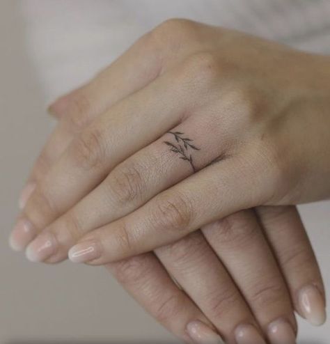 70+ unique and striking finger tattoo designs: symbols, hennas, roses, snakes, dots, lettering, hearts, and wedding rings for couples. Bonus: tattoo meanings. Finger Cute Tattoos For Women, Delicate Ring Finger Tattoo, Vine Wedding Ring Tattoo, Finger Tattoos Feminine, Women Wedding Ring Tattoo, Women Ring Tattoo, Ring Finger Tattoos For Women Meaningful, Leaf Ring Tattoo, Women’s Ring Tattoo