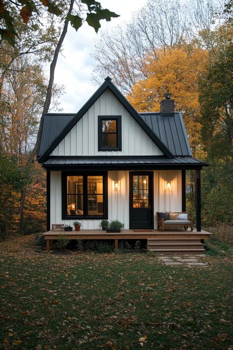 Small elongated cottage house with black and white siding metal roof small porch. Fall in love with these small but charming and cozy small houses, from cottages to modern cabins. Live tiny at large! Wrap Around Porch Cottage, Small Cottage House Exterior, Tiny Home With Fireplace, Modern Farmhouse Tiny House, Tiny House Guest House, Small Tudor House Plans, Wood House Design Exterior, Tiny Home Building Plans, Small Nice Houses